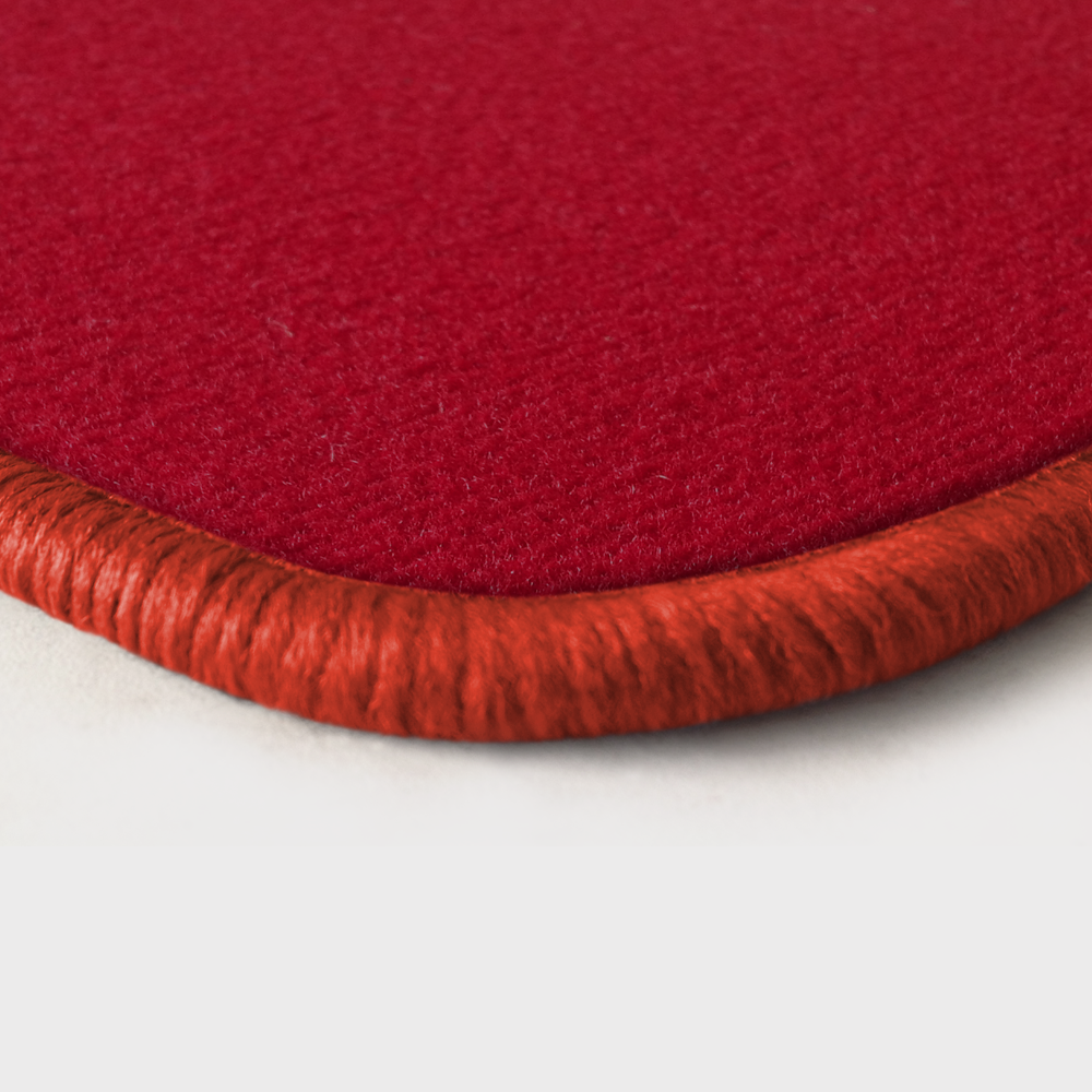 Eine Ecke als Beispiel einer Fussmatte Velours rot mit Rand in orange.